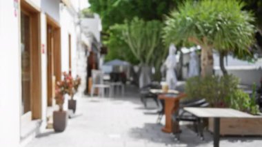 Ianzarote İspanya 'daki açık hava restoranı. Ağaçların bulanık arkaplanı ve parlak güneş ışığı altındaki masalar ve sandalyeler kanarya adalarında huzur verici bir bokeh etkisi yaratıyor.