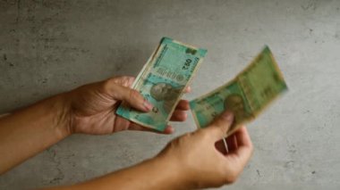 Elleri ve parmakları beton bir arka plan karşısında Hindistan 'dan gelen rupileri sayan adam net bir şekilde finansal işlem sahnesini resmediyor..