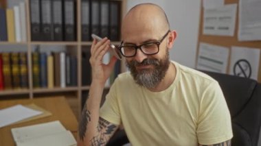 Ofiste telefonla konuşan ve arka planda kitap rafları olan bir adam.