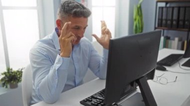 Ofisteki başarısını kutlayan orta yaşlı bir adam masasında bir bilgisayar monitörüyle mutluluğunu gösteriyor.