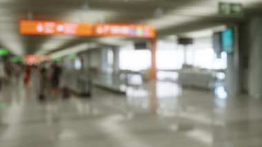 Bulanık gezginler arka planda çözünmüş işaret ve terminal ile havaalanında yürürken, bokeh etkisini ve yoğun atmosferi yakalıyorlar..