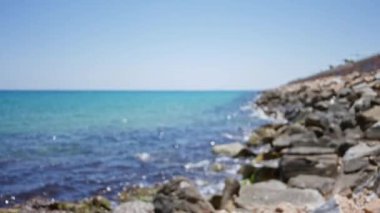 Bulanık deniz kıyıları berrak mavi su ve kayalık kıyı şeridi güneşli bir gökyüzünün altında okyanus ufkuna odaklanıyor.