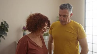 Orta yaşlı çift rahat bir oturma odasında birlikte gülümsüyor..