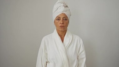 Uyarı ifadesi, bornoz ve havlu giymiş orta yaşlı bir kadın, avucunun içinde izole edilmiş beyaz arka plan ile ciddi bir dur hareketi gösteriyor.