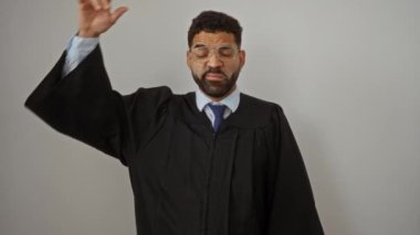 Yargıç cüppesi, Latin kökenli genç bir adam şüpheli ve düşünceli bir ifadeyle duruyor, soru üzerine kafası karışık - beyaz arka planda izole edilmiş.