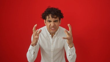Beyaz gömlekli hayal kırıklığına uğramış genç bir İspanyol öfkesini canlı kırmızı bir arka planda dışa vuruyor.