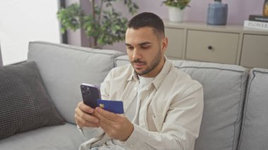 Akıllı telefon kullanan ve kredi kartını kapalı koltukta tutan yakışıklı bir İspanyol.