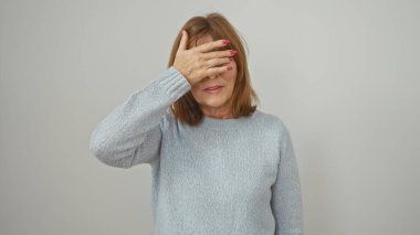 Olgun bir kadın, elini beyaz izole bir arka plana sürerek gözlerini kapatır. Kaçınma ya da şaşırma kavramlarını hatırlatır.