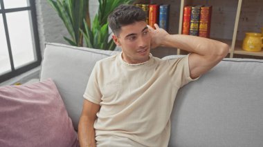 Yakışıklı ispanyol adam, kanepede otururken dinlerken el kol hareketi yapıyor.