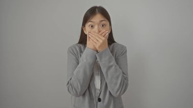 Şaşırmış Asyalı kadın elleriyle ağzını kapatıyor, beyaz tenli.
