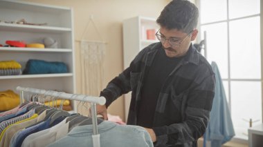 Genç İspanyol adam iyi organize edilmiş, parlak bir soyunma odasında kıyafetlerini karıştırıyor..