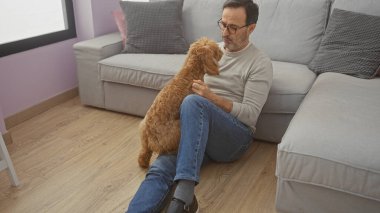 Orta yaşlı İspanyol bir adam sıcak bir oturma odasında kanişiyle sevgi dolu bir şekilde iletişim kurar..