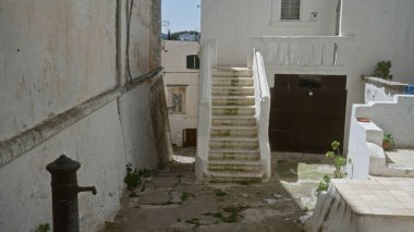 Kırsal beyazlatılmış binaları, yıpranmış duvarları ve tarihi bir şehir olan Oostuni, Puglia, İtalya 'da gündüz vakti merdiveni gösteren bir açık hava sahnesi..