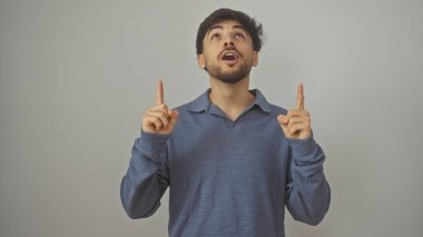 Beyaz bir arka planda dikilirken yukarı bakan sakallı yakışıklı bir Arap.