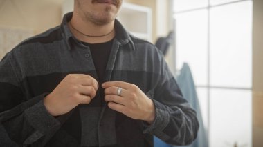 Genç İspanyol bir adam fanila gömleği ilikliyor. Sıradan bir görünüm için.