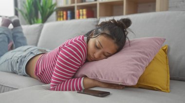 Genç İspanyol kadın evinde, yanında akıllı telefonuyla uyukluyor, rahatlama ve yaşam tarzını resmediyor..