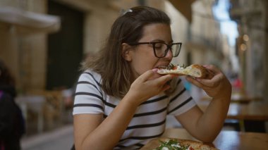 Genç bir İspanyol kadın İtalya 'da bir restoranın terasında pizza yemekten hoşlanıyor..