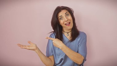 Mavili İspanyol kadın elini pembe arka planda gezdiriyor, şaşırdığını ve işaret ediyor..