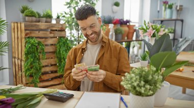 Gülümseyen İspanyol adam çiçekçi dükkanında para sayıyor, dostane bir iş ortamı yaratıyor..