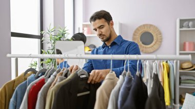 Yakışıklı İspanyol adam modern bir kapalı dolap odasında kıyafet seçiyor.