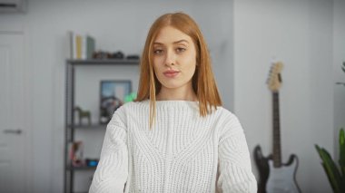 Oturma odasında rahat bir genç kadının portresi. Arka planda gitarı var. Rastgele bir zarafet ve konfor yayıyor..