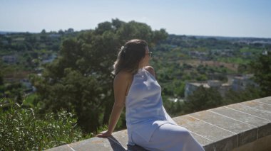 Genç bir İspanyol kadın, locorotondo, puglia, İtalya 'daki zengin manzaranın ve tarihi binaların güzel manzarasının keyfini çıkarıyor. Parlak, güneşli bir günde manzaralı, eski bir kasabanın bakış açısından..