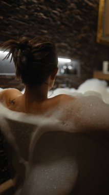 Huzurlu bir kadın zarif bir banyoda lüks bir köpük banyosundan zevk alır. Rahatlama ve kendine bakımı çağrıştırır..