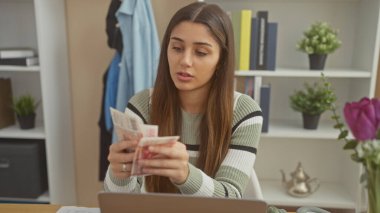 İspanyol kadın modern bir ev dekorunda İzlanda kronu sayıyor..