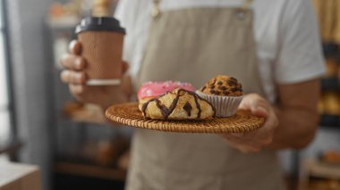 Orta yaşlı bir adam fırında elinde bir tepsi hamur işi ve elinde bir kahve fincanı tutuyordu.