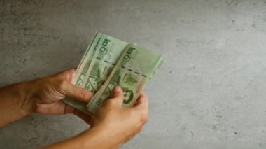 Tay baht gagalarını tutan ve sayan adam beton bir arka planda..