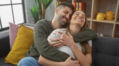 Sevgi dolu bir çift, sıcak bir oturma odasında kanepede kucaklaşıp, mutluluğu ve birlikteliği ifade ediyorlar..