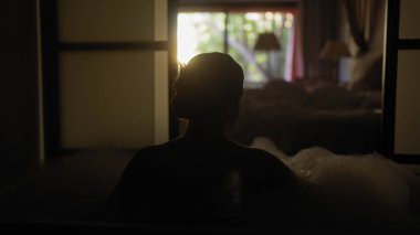 Sakin, genç bir İspanyol kadın lüks bir otel odasında rahatlatıcı bir köpük banyosunun keyfini çıkarıyor..