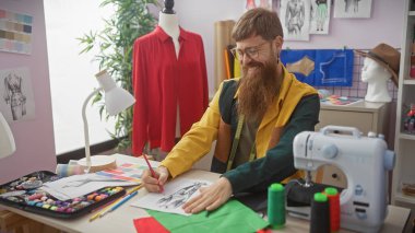 Sakallı adam renkli bir terzi dükkanında dikiş dikiyor.