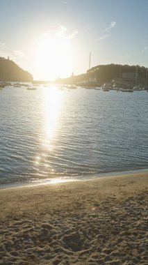 Serene Mallorca günbatımı sakin suyla birlikte limanda, yelkenlileri ve İspanya 'daki kumlu plajı yansıtıyor..