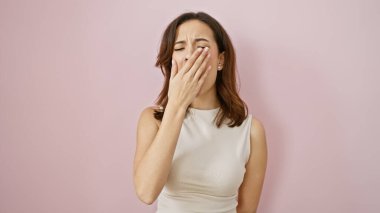 Pembe arka planda esneyen yorgun, genç bir İspanyol kadın. Yorgun bir anı canlandırıyor..