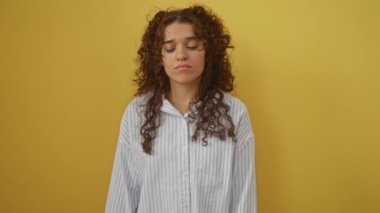 Genç İspanyol kadın ayakta dikilip ağlıyor, üzgün, depresif, stresli yüz ifadesi, izole edilmiş sarı arka plan için endişe, öfke ve üzüntü gösteriyor.
