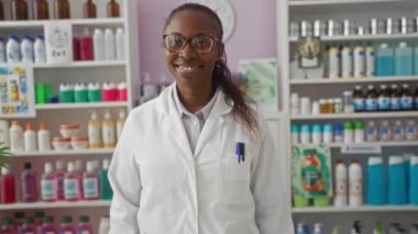 Laboratuvar önlüklü bir kadın eczacı iyi stoklanmış bir eczanede el kol hareketleri yapıyor..