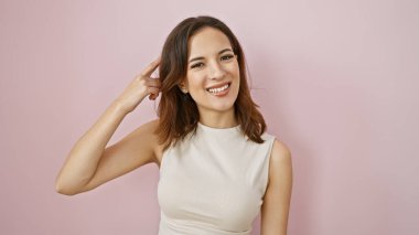 Gülümseyen, modaya uygun saç stili olan genç İspanyol kadın kafasını pembe bir duvara dayadı..