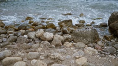 Dalgaların çakıl taşlarına çarptığı kayalık sahil kıyısı sakin bir açık hava ortamında deniz kıyısına yakın..