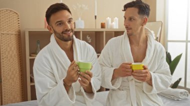 Bornozlu iki adam sıhhatli bir kaplıcada kahvenin tadını çıkarıyorlar. Kapalı bir mekanda sevgi ve arkadaşlık yayıyorlar..