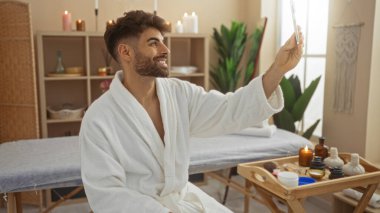 Yakışıklı bir adam sıhhatli bir salonda selfie çekerken evde spa deneyimi yaşıyor.