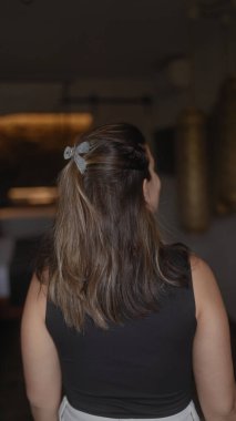 Uzun esmer saçlı, siyah bluzlu, sıradan bir tarzı ve sadeliği tasvir eden bir kadının arka plan görüntüsü..