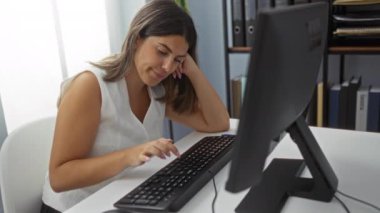 Ofis ortamında bilgisayarın başında çalışan bir kadın. Klavyeye yazarken odaklanmış ve meşgul görünüyor.