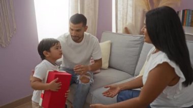 Çocuk kucaklama, hediye konuşma, kadın ve adamla oturma odasında, sıcak bir yuva kurma ortamında ailecek eğlenme.