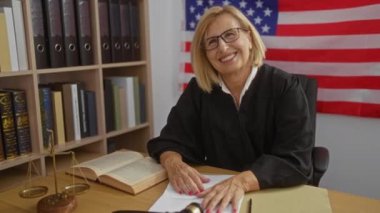 Kadın yargıç arka planda kitap ve adalet terazileriyle bir Amerikan mahkemesinde gülümsüyor.