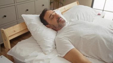 Huzurlu bir yatak odası ortamında yatağa uzanmış, dingin ve dinç görünen bir adam.