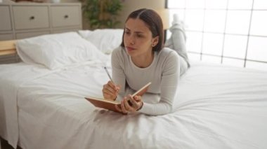 Parlak bir yatak odasındaki yatakta uzanan bir kadın, esmer, genç, kadın, yetişkin, çekici, ev, ev, ev, oda, rahat atmosfer.