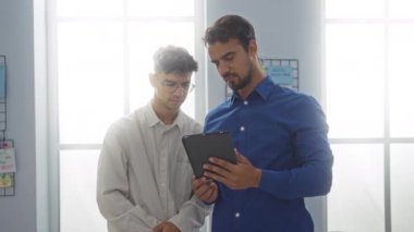 Bir ofis ortamında birlikte çalışan erkekler, elinde tablet olan bir adam, ortak çalışma alanına göz atma imkanı sağlıyor..