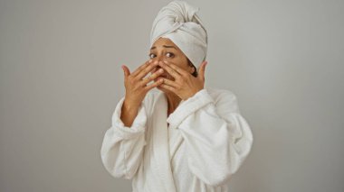 Bornoz ve havlu giymiş, yüzü beyaz arka planda soyutlanmış bir kadın.