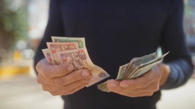 Gündelik giysiler içinde orta yaşlı bir adam güneşli bir ortamda birleşik Arap emirliklerini sayıyor..